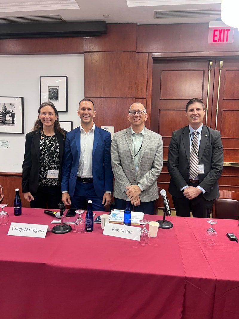 Star Lab founder Alison Rini, far left, with three fellow panelists behind a table with a red tablecloth, microphones and name cards.